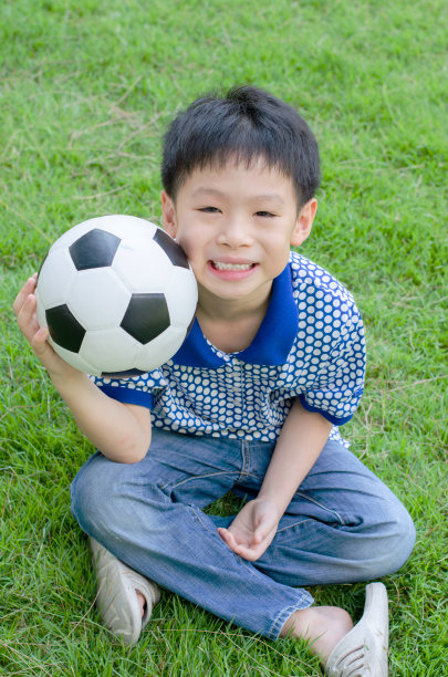 小男孩带着球在草地上图片下载