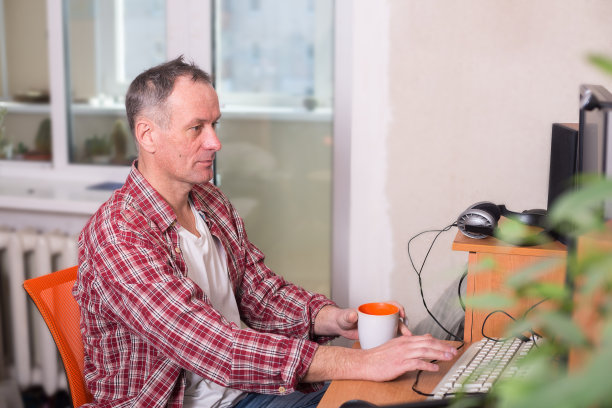 一个人拿着一杯咖啡坐在电脑旁边图片下载