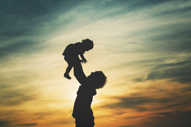 父亲和小女儿的剪影在夕阳下玩耍素材图片