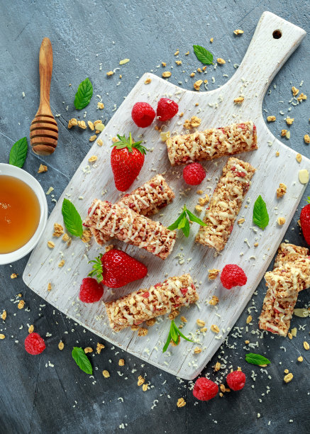 加草莓，覆盆子蜂蜜和白巧克力的格兰诺拉燕麦棒放在切菜板上图片下载