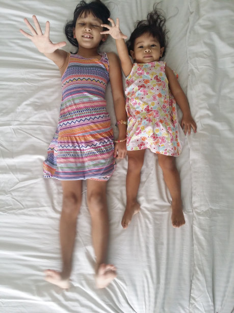 两个小女孩躺在床上，一起玩耍图片下载