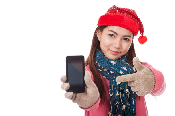带着红色圣诞帽的亚洲女孩指着手机图片下载
