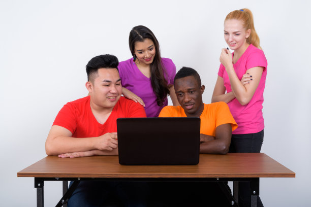 工作室拍摄了一群快乐的不同民族的朋友在一起用笔记本电脑聊天和微笑图片下载