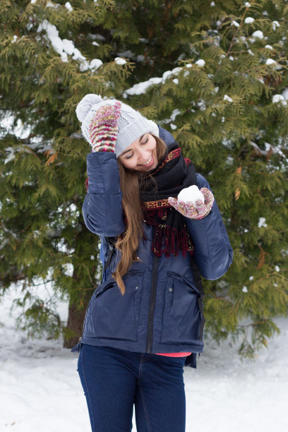 美丽的女孩在公园里玩雪球，在冬天图片下载