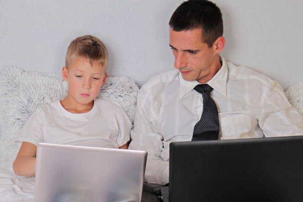商人父亲和儿子都使用笔记本电脑。图片下载