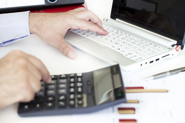 在办公室里用电脑和计算器工作的商人图片下载