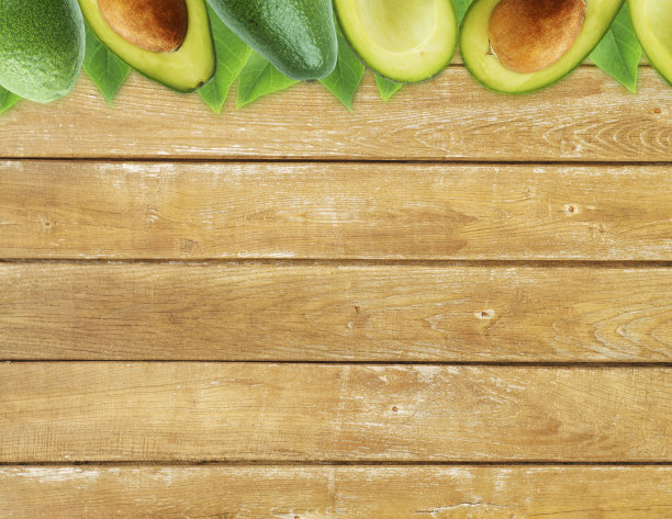 新鲜牛油果和树叶在木制背景。图片下载