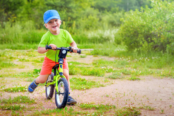 骑着自行车的男孩在运动。一个男孩骑着一顶帽子在运动。一个骑自行车的男孩脸上带着满意的表情。图片下载