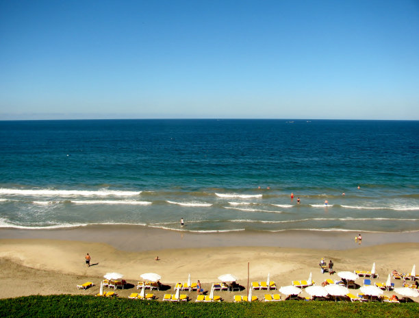 人们在海滩上用日光浴床和雨伞图片下载