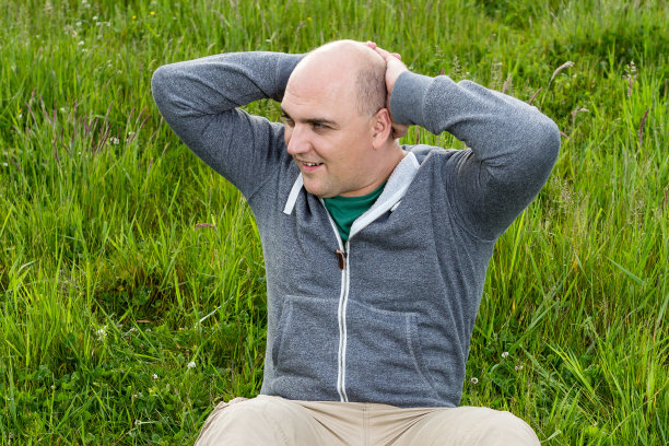 在绿色草地上做仰卧起坐的人，特写图片下载