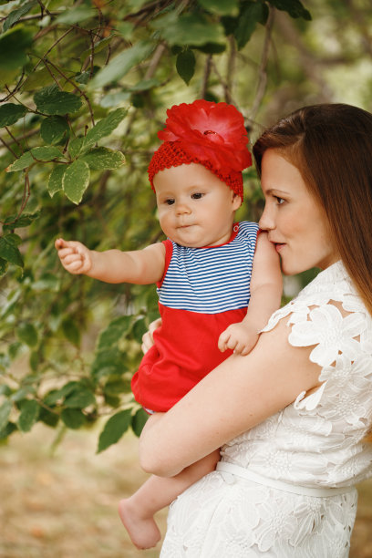 慈爱的年轻母亲抱着并亲吻她的孩子图片下载