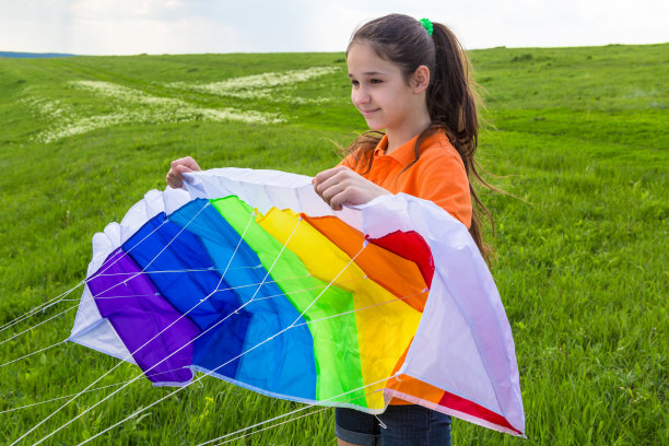 女孩拿着五颜六色的风筝在绿色的草坪上图片下载