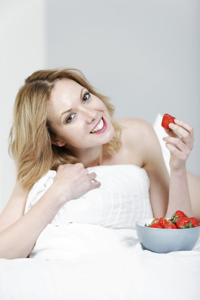一个女人躺在床上，手里拿着草莓图片下载