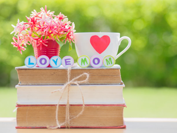 母亲节概念。书、礼物、茶杯上的爱妈字母，背景是红心和花朵图片下载