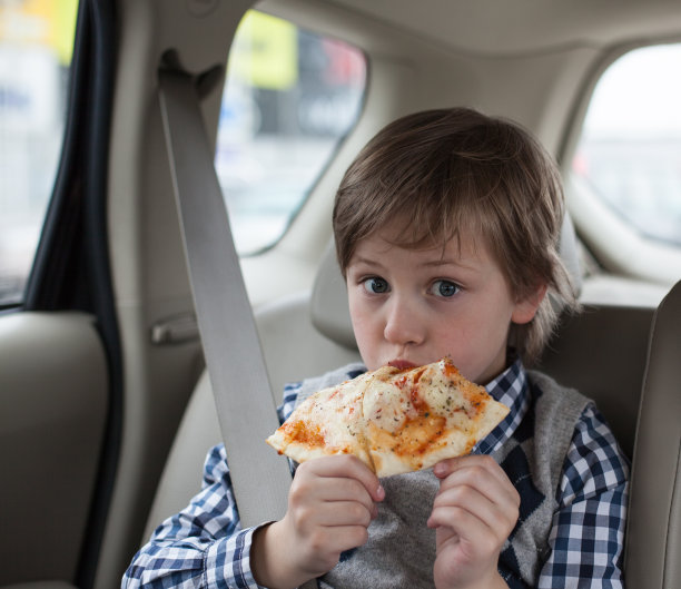 男孩系安全带，在车里吃披萨图片下载