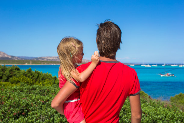 年轻的父亲和小女孩正在欣赏美丽的海景图片下载