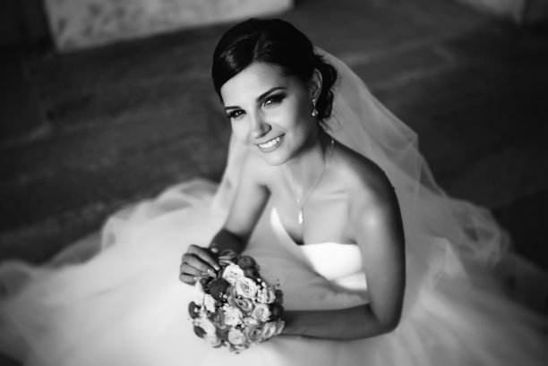 新娘手捧花束，面带微笑。婚礼肖像美丽的新娘。的婚礼。结婚的那一天。黑色和白色。素材图片