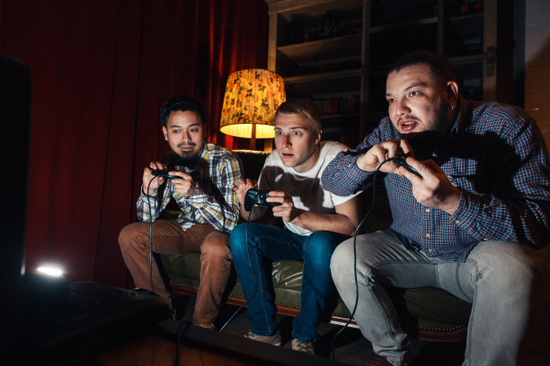 三个精神高度集中的年轻人玩电子游戏图片下载