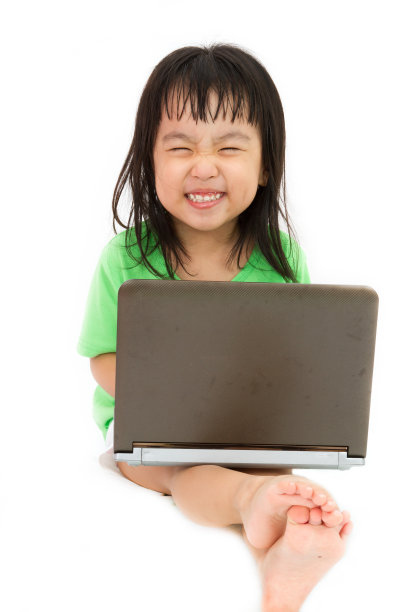 一个中国小女孩坐在地板上，拿着笔记本电脑图片下载