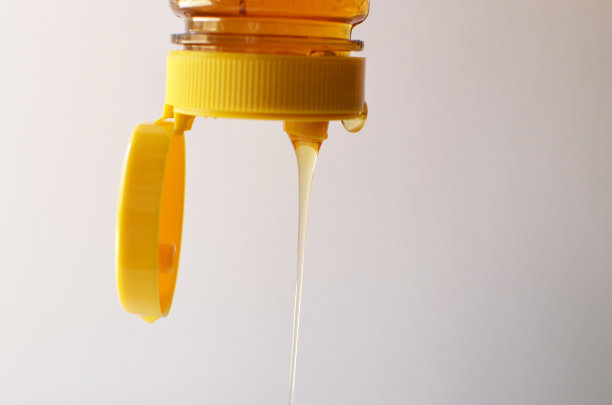 蜂蜜从带黄色盖子的瓶子里倒出来图片下载