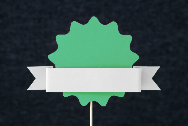 绿色的证书、徽章、印章或横幅模板，上面用纸或硬纸板剪成白色、浅灰色的带子。手工模型的设计保修或奖励。圆形贴纸造型。图片下载