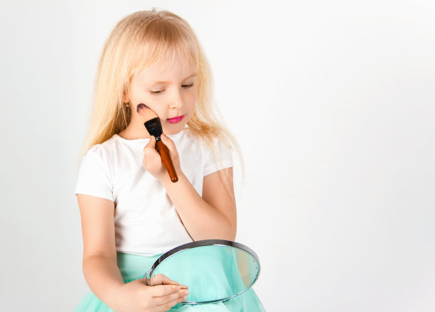 小女孩开心地看着镜子里彩色的脸，在白色的背景上图片下载