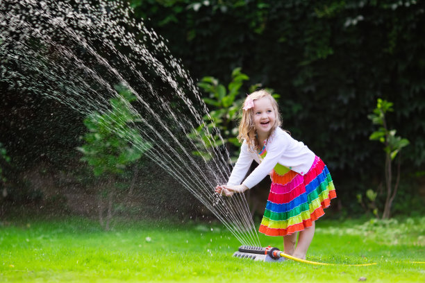 可爱的小女孩玩花园洒水器图片下载