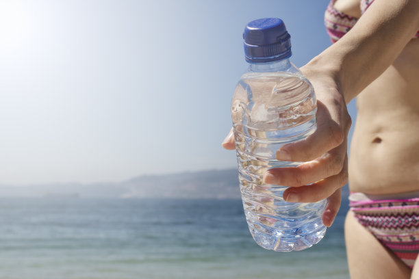 女人的手捧着太阳下的一瓶水图片下载