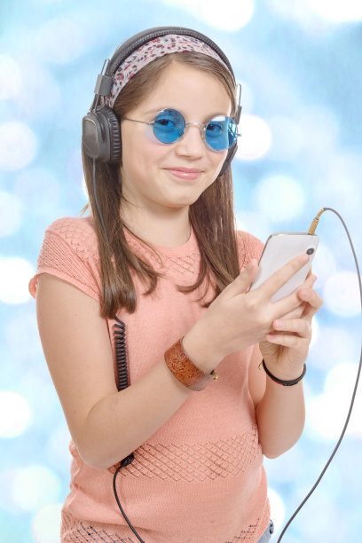 小女孩用他的智能手机听音乐，散焦背图片下载