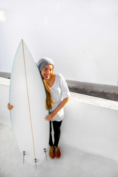 在白色的城市背景上，带着冲浪板的女人图片下载