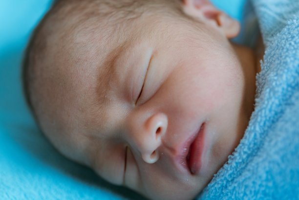 新生的亚洲婴儿睡觉时盖着蓝色的布图片下载