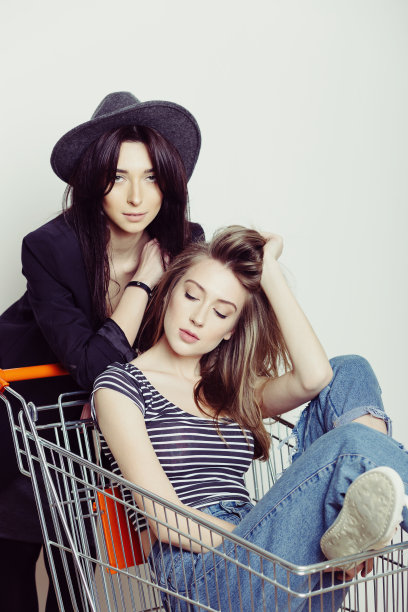 两个快乐美丽的少女在室内驾驶购物车图片下载