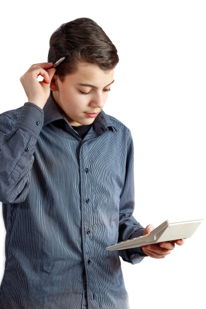 一个用计算器的少年。为杂志工作的男孩图片下载