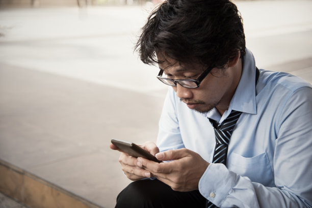 男员工拿着智能手机，用它来严肃地对待一些事情。图片下载