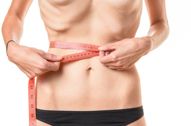 体重不足的年轻女子在测量她的腰围图片下载