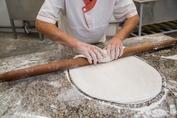 手用擀面杖在木桌上烘烤生面团图片下载