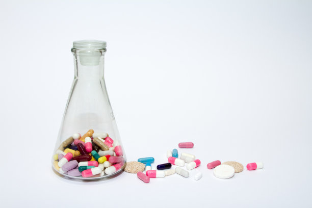 彩色的药丸在一个玻璃容器在白色的背景。图片下载