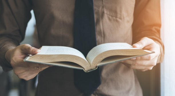 商人站在窗边，用复古的语气读着书。图片下载