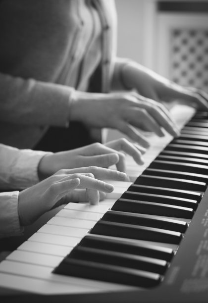 一个女人在教小女孩弹钢琴。黑白照片。图片下载