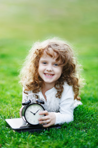 小女生在秋天公园的草坪上休息。图片下载