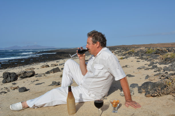 在海滩上喝红酒的快乐男人图片下载