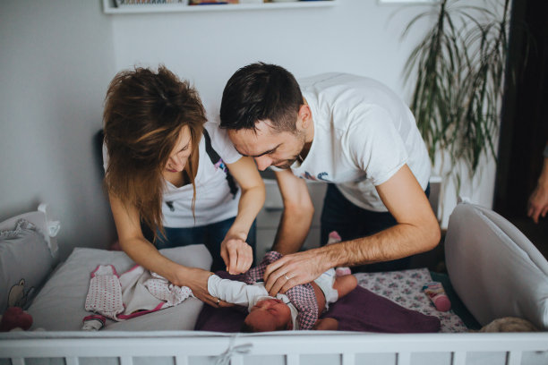 父母给新生婴儿穿衣服素材图片