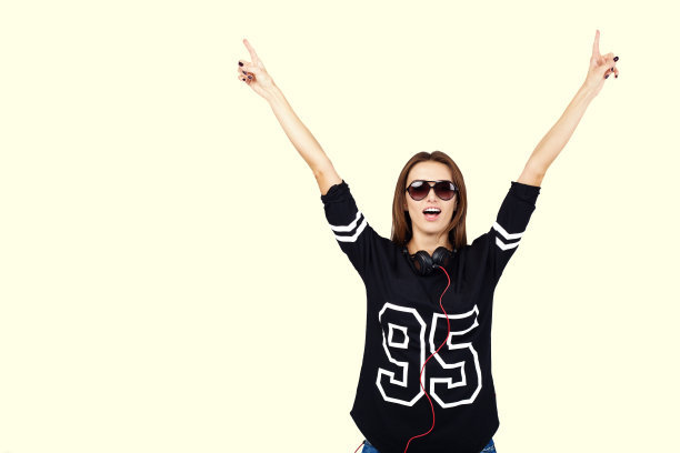 穿着牛仔裤和黑衬衫，戴着耳机的女DJ。微笑图片下载