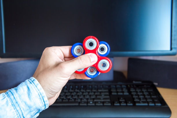 男子的手拿着两个多色的纺纱机背景上的一个个人电脑特写图片下载