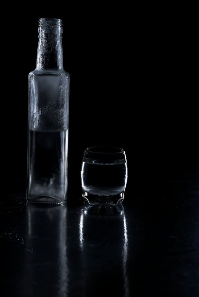 黑色背景上的冰冻伏特加酒瓶和玻璃杯图片下载