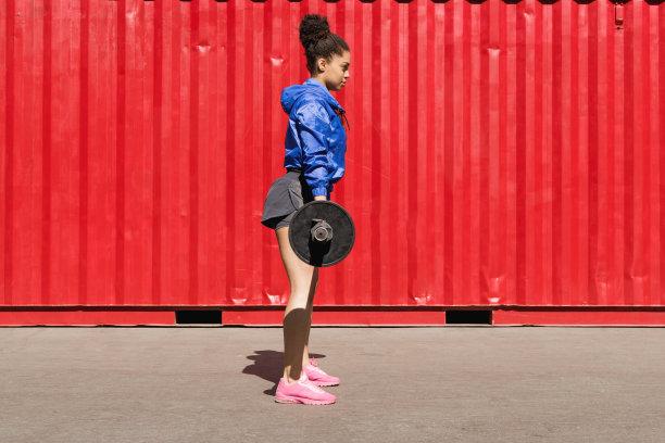 穿着运动服在户外练杠铃的年轻女子图片下载