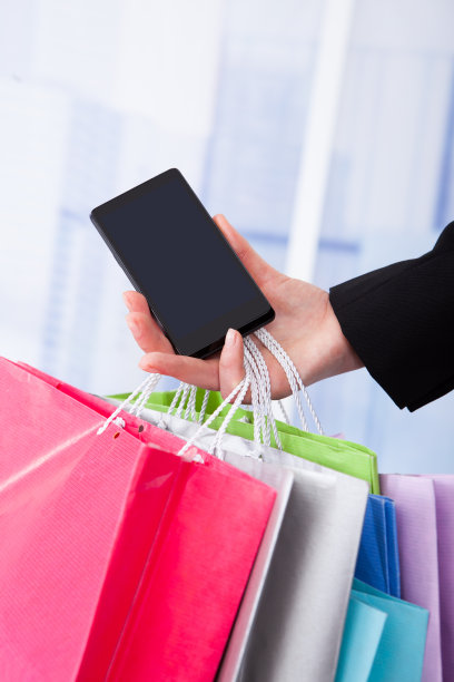 拥有智能手机和购物袋的女商人图片下载
