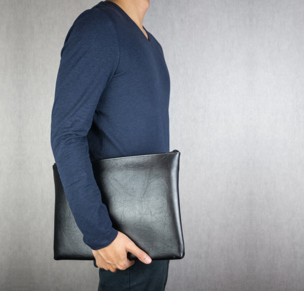 一个男人拿着皮包，站在浅灰色的背景上图片下载