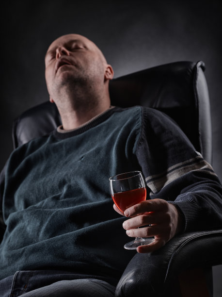 睡着的中年酒鬼和酒杯图片下载