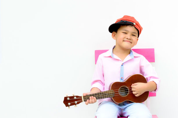 肖像聪明的亚洲孩子玩尤克里里图片下载